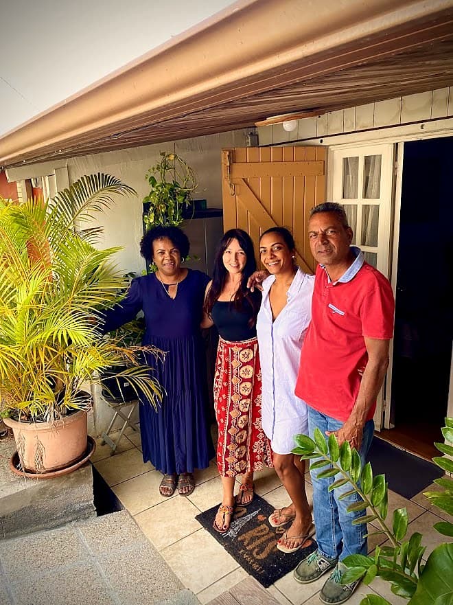 Cuatro habitantes de La Reunión sonrientes delante de su casa criolla